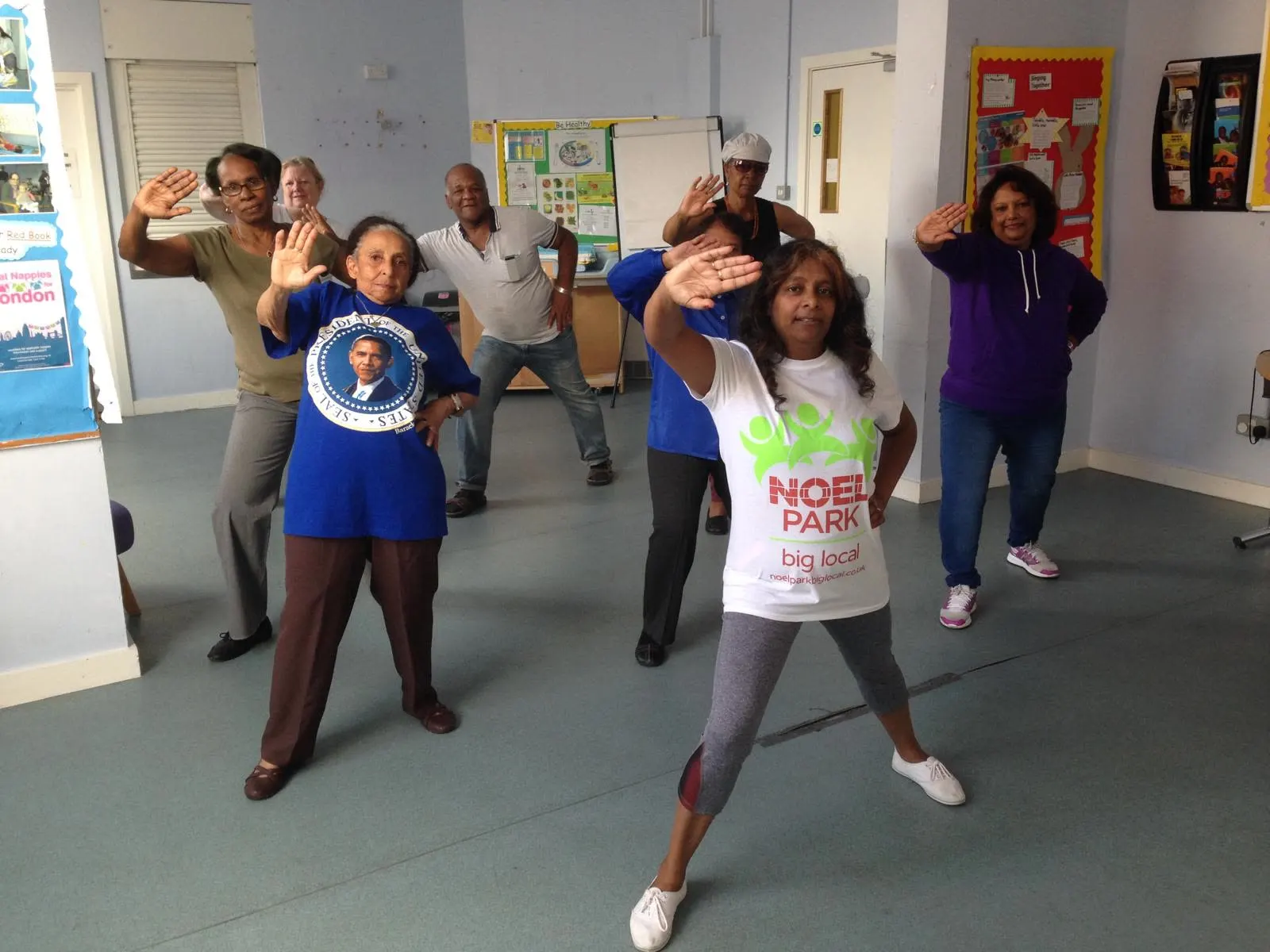 Members holding a pose with one hand raised in a community room