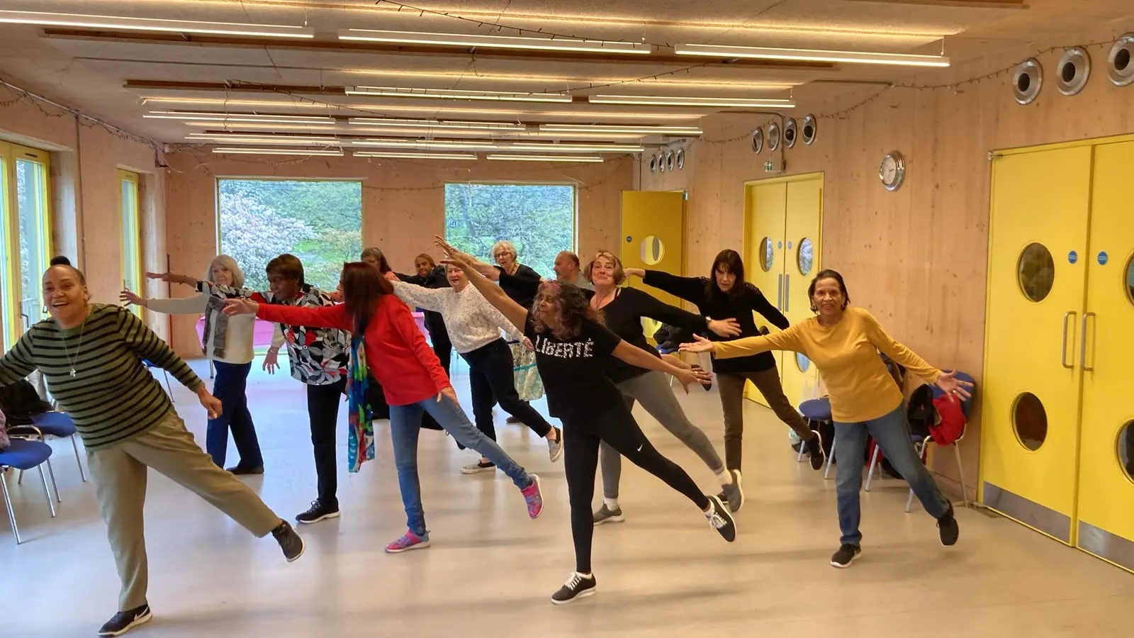 Members in a line stretching arms out and extending one leg behind